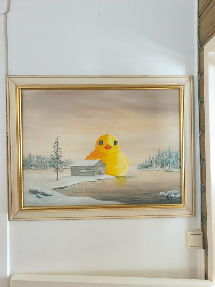 Thrifted painting of a snowy landscape with a large, funny yellow rubber duck added for a humorous twist.