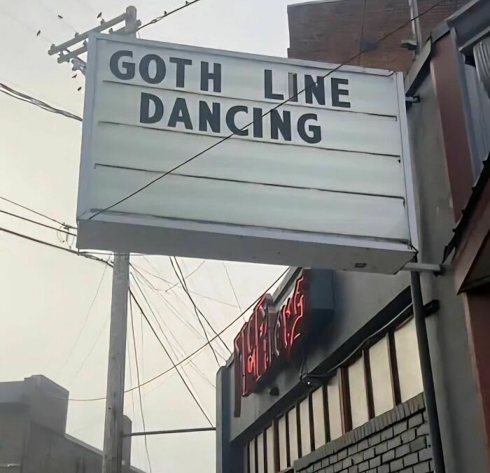 Outdoor sign displaying funny stupid signs pics with text Goth Line Dancing above a building with a neon sign.