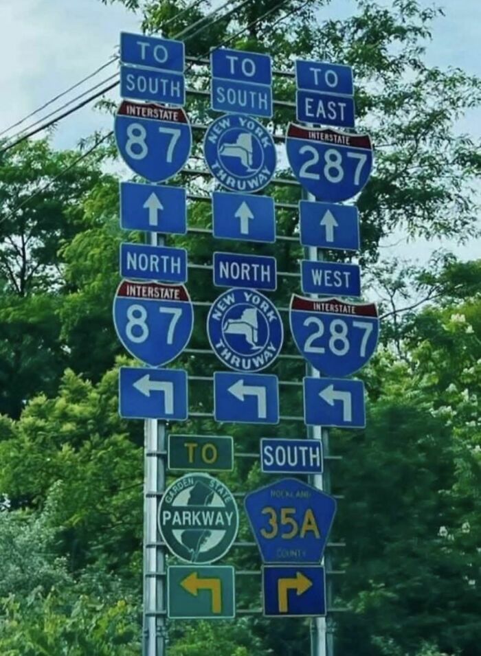 Multiple confusing road signs pointing in different directions creating a funny stupid signs pics moment on a highway.