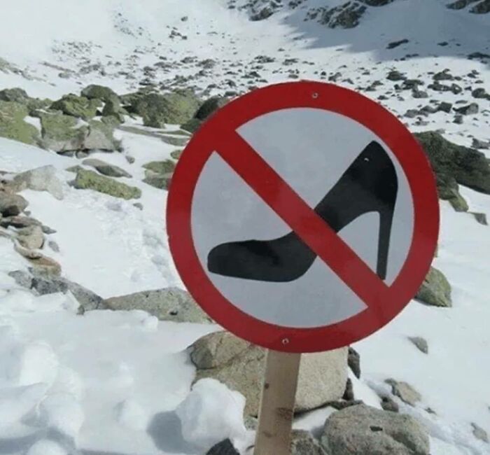 No high heels allowed sign placed in snowy mountainous terrain, funny stupid signs pics highlighting impractical footwear warnings.