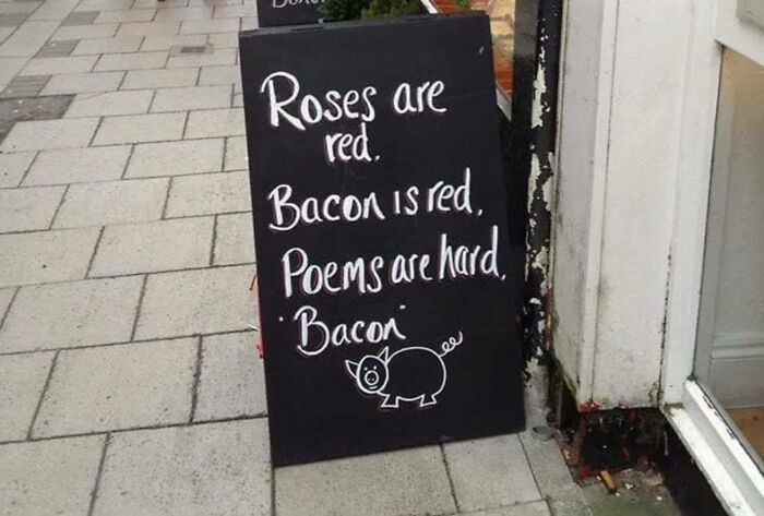 Chalkboard sign on sidewalk with funny stupid signs pics poem about bacon and a pig drawing outside a store.