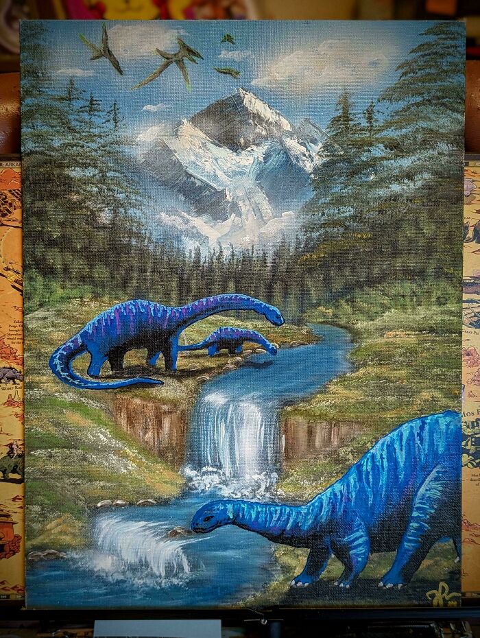 Personalized thrifted painting showing blue dinosaurs by a waterfall with mountains and birds in the background.