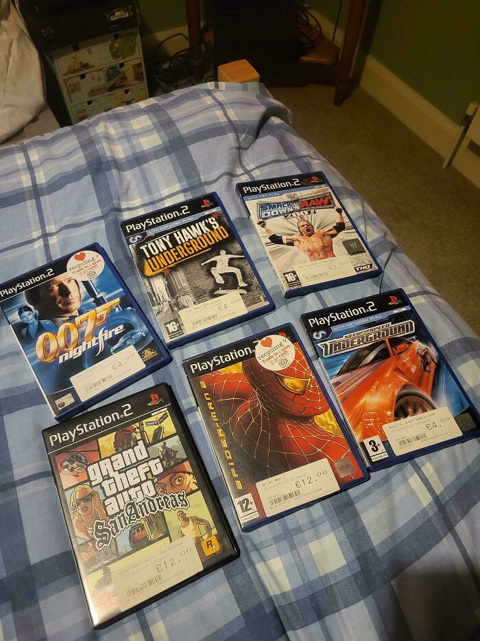 PlayStation 2 games including Tony Hawk's Underground and Grand Theft Auto on a bed evoking 90s and 2000s nostalgia.