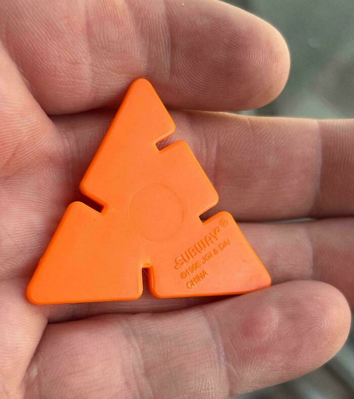 Hand holding an orange plastic piece from a 90s and 2000s nostalgia toy or game, evoking childhood memories.