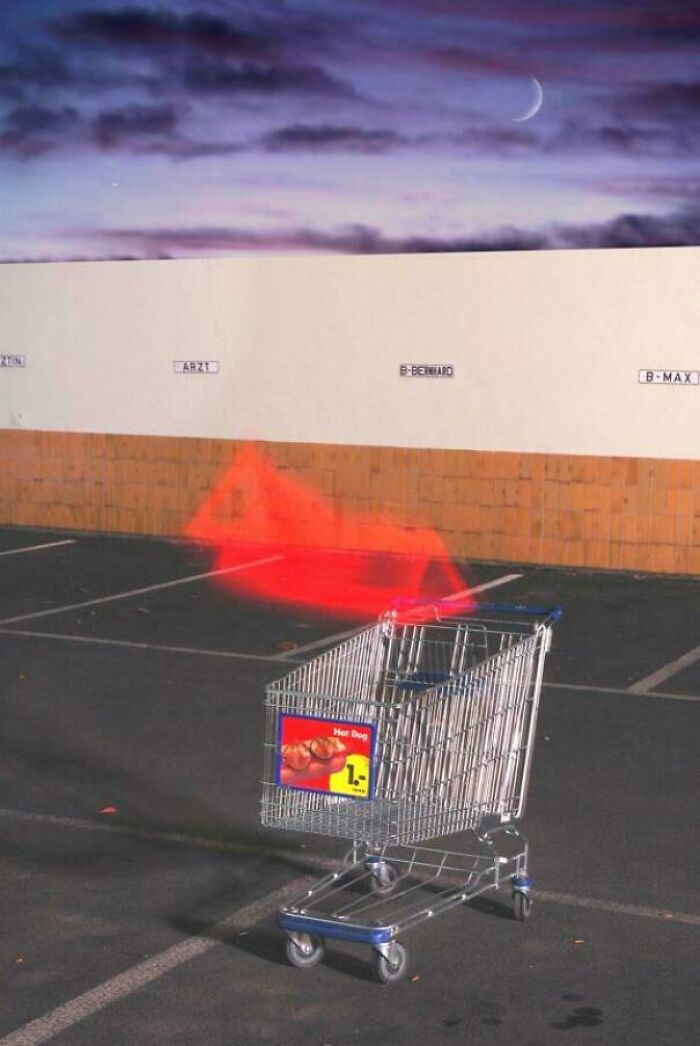 Shopping cart with a glowing red toy car illusion in an empty parking lot at dusk, evoking 90s and 2000s nostalgia.