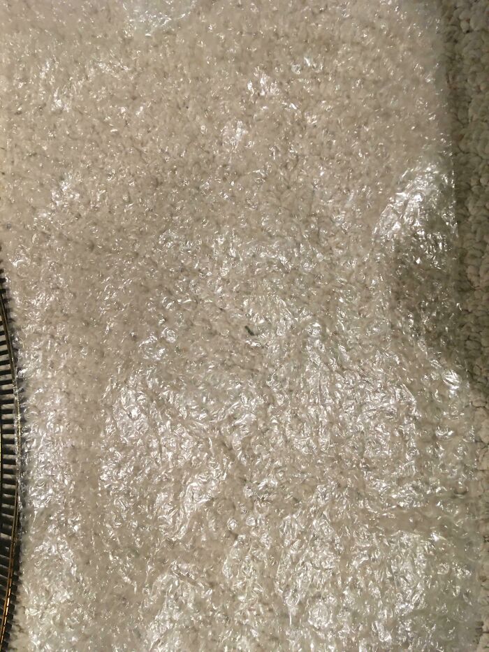 Plástico de burbujas transparente sobre alfombra beige, detalle de textura que simboliza momentos incómodos en Secret Santa laboral.