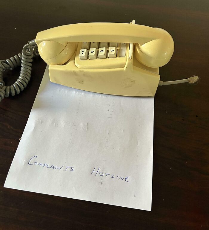 Funny pictures 2025 vintage yellow telephone on paper labeled Complaints Hotline on dark wood table