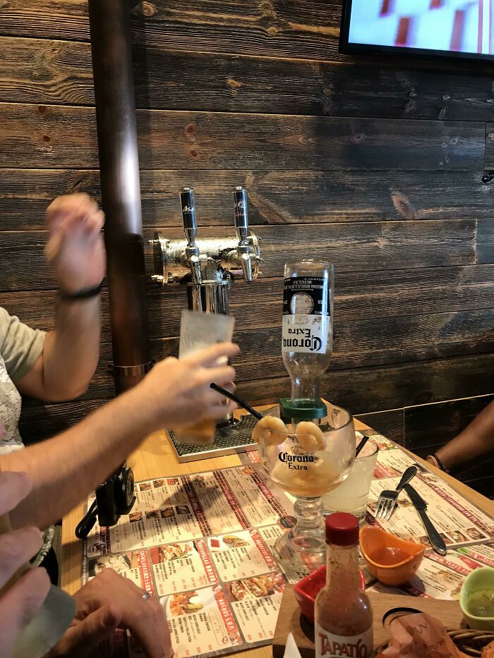 Person serving beer from a tap with a Corona Extra bottle in a shrimp cocktail, showcasing impressive country beverage ideas.
