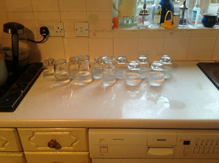 Several upside-down water glasses on a kitchen counter, showcasing fun sibling moments with playful arrangements.