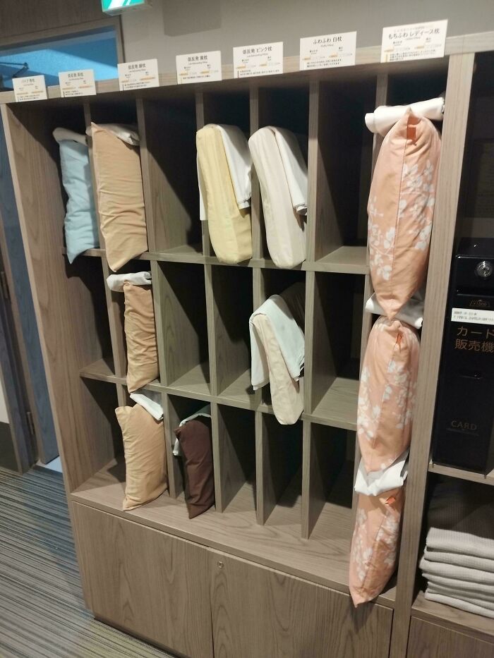 Shelf with various pillows organized neatly in a public space, showcasing impressive things countries implemented for visitor comfort.
