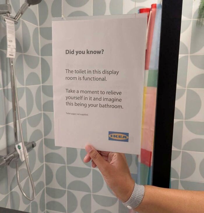 Funny Pictures - IKEA bathroom display sign says toilet is functional, hand holding sign in showroom shower