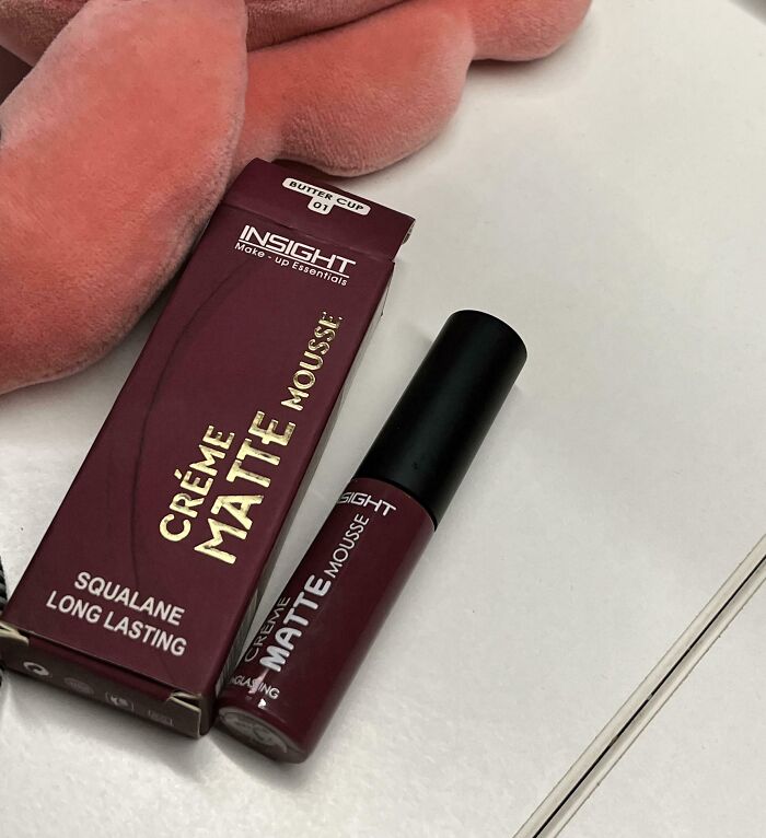 Labial mate en mousse junto a caja y peluche rosa, simbolizando un regalo fallido de Secret Santa en oficina.