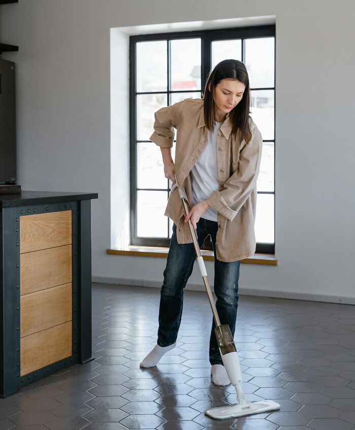 Woman cleaning floor with mop in a bright room, symbolizing people sharing biggest family secrets and personal stories.