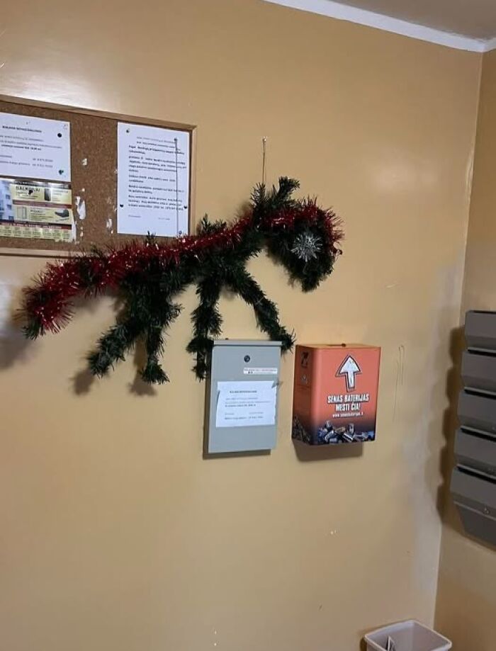 Unconventional Christmas decoration in a Lithuanian apartment building hallway using tinsel and garland shaped like an animal.