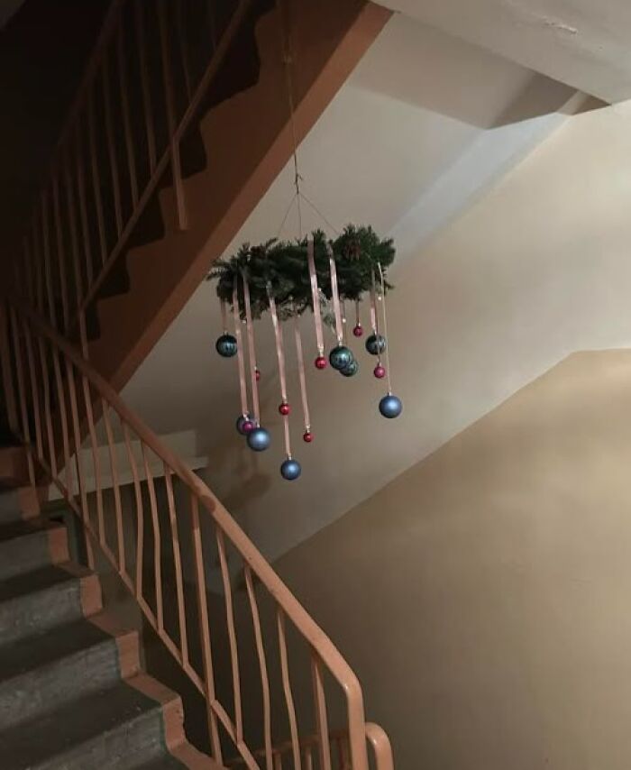 Apartment building staircase decorated with a hanging Christmas wreath and ornaments, showcasing Lithuanian holiday decor.