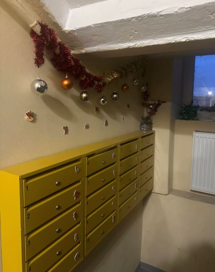 Yellow apartment mailboxes decorated with Christmas ornaments in a typical Lithuanian sad apartment building hallway.
