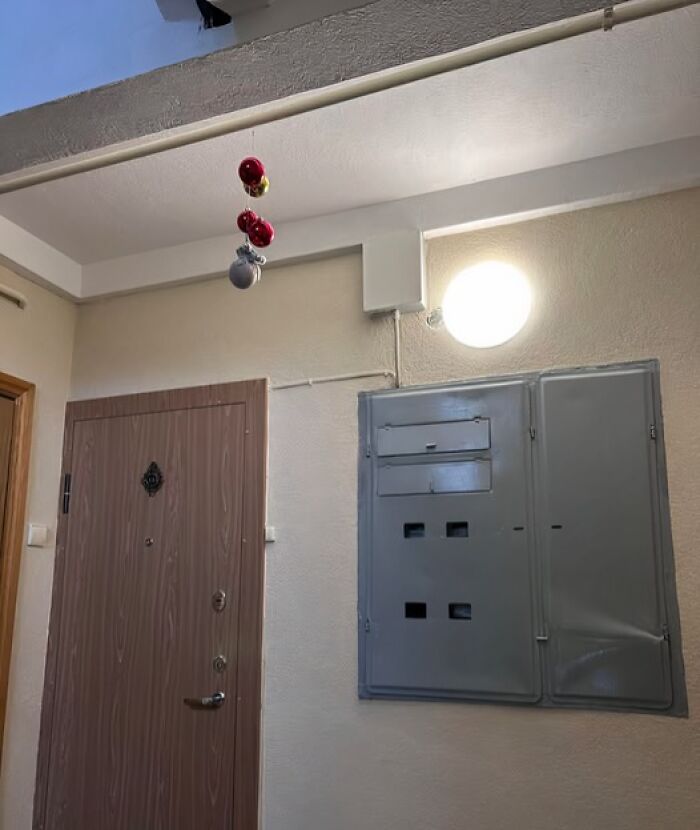 Minimal Christmas decorations with hanging ornaments in a dull Lithuanian apartment building hallway.