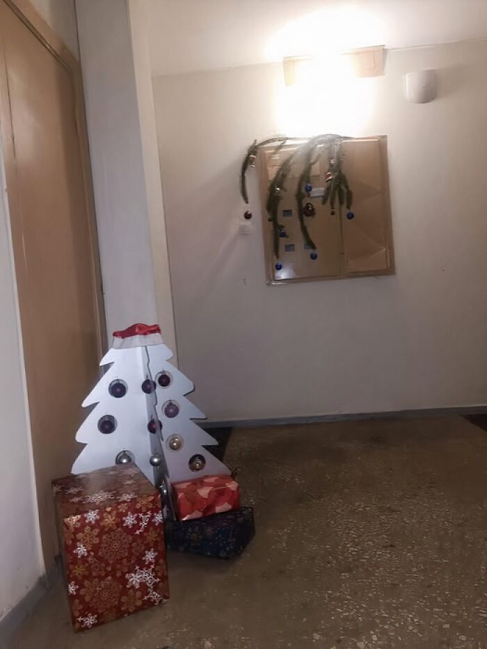 Minimalist Lithuanian Christmas decoration in an apartment building hallway featuring a simple white tree and wrapped presents.