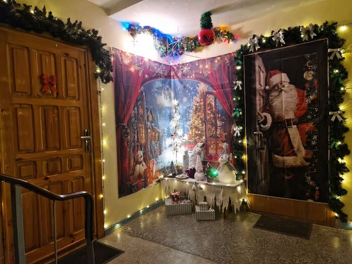 Christmas decorations on an apartment hallway wall featuring Santa, snowy scenes, and festive lights in a Lithuanian building.