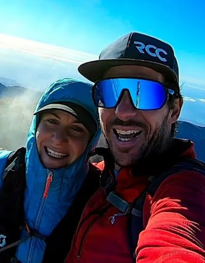 Couple in outdoor gear smiling during a mountain hike, related to woman abandoned to fatally freeze on Austria&rsquo;s highest peak.