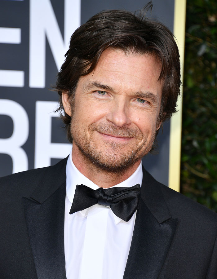 Jason Bateman smiling in a black tuxedo at a formal event, raising eyebrows with a remark about sister Justine.