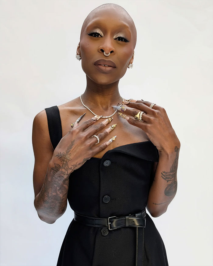 Cynthia Erivo posing with elaborate rings and manicured nails, highlighting her oddly large hands in a black dress.