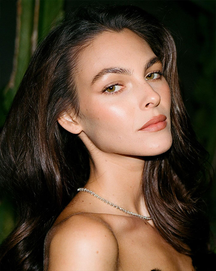 Close-up portrait of a woman with long dark hair and natural makeup, spotlighting Jennifer Lawrence and DiCaprio dating history discussion.