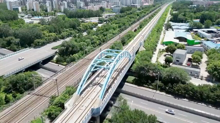 Aerial view of remarkable engineering on a long Beijing Grand Bridge, China spanning highways and railway lines in an urban area with greenery.