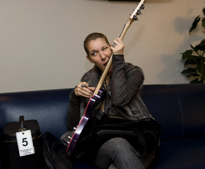 Celine Dion with a rare condition playing guitar on a couch, showcasing celebrities with rare conditions in a personal moment.