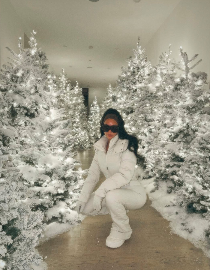 Kim Kardashian dressed in white, surrounded by glowing Christmas trees, reflecting fans' views on her kids' home life.