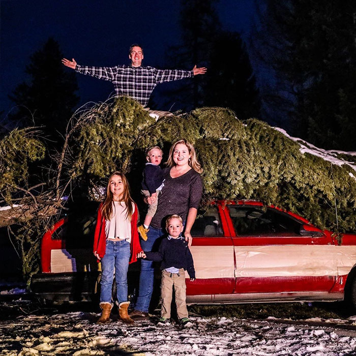 Man and family with large Christmas tree on car roof at night, representing viral Christmas lawyer taking on HOA and winning.