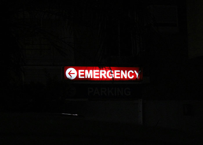 Emergency sign glowing at night outside hospital, symbolizing urgency related to patient’s haunting final post before fatal dental procedure Emergency sign glowing at night outside hospital, symbolizing urgency related to patient’s haunting final post before fatal dental procedure