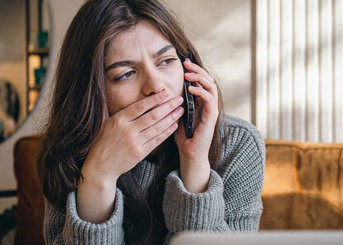 Woman covering her mouth while making a phone call, illustrating 911 operators handling non-emergency calls.