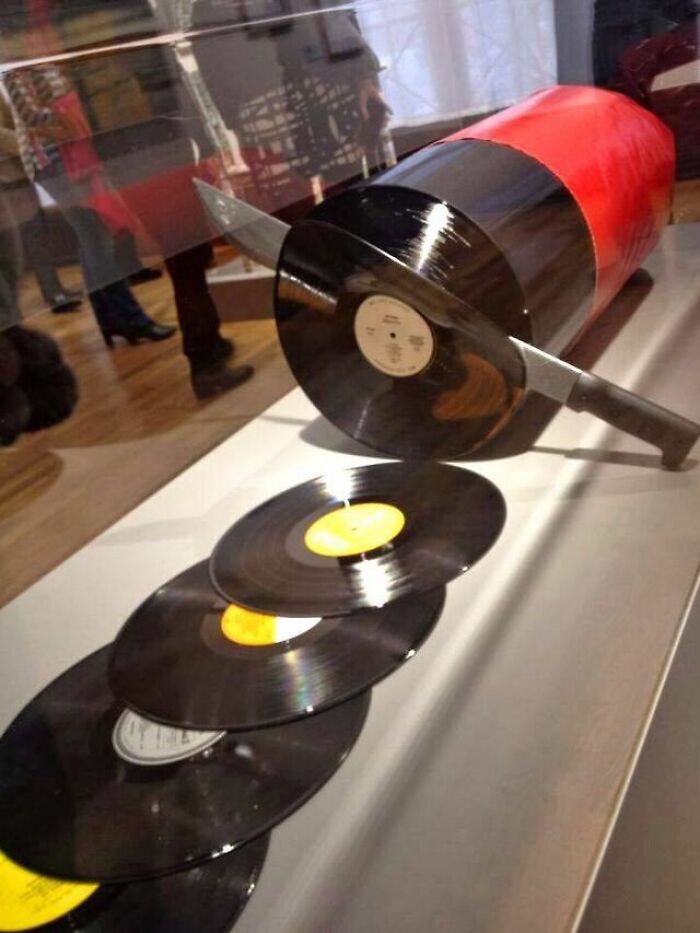 Trippy picture of a large cylindrical object sliced by a knife revealing vinyl records inside, creating a surreal visual effect.