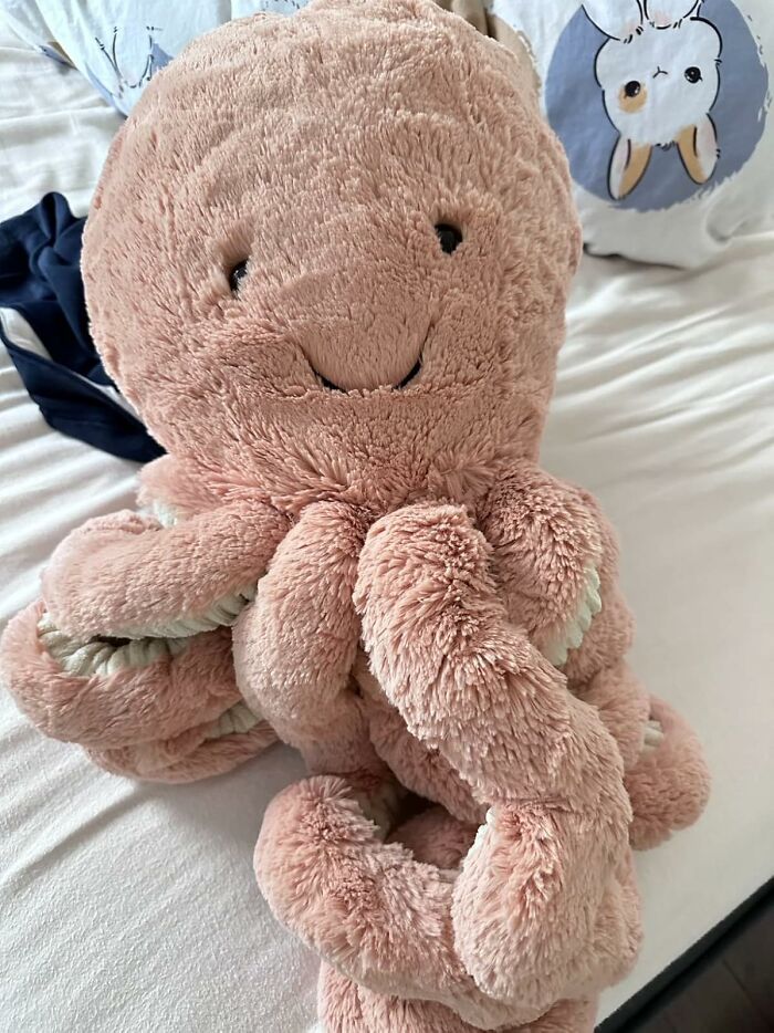 Soft pink octopus plush toy on a bed, a popular gift among teens this holiday season.