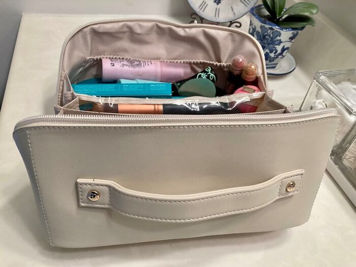 Beige makeup bag open on a table, filled with beauty products, a gift idea to impress your mother-in-law.