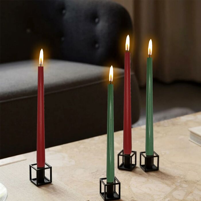 Four lit red and green tapered candles in black cube holders on a table, perfect gifts found in an isle at Hobby Lobby.