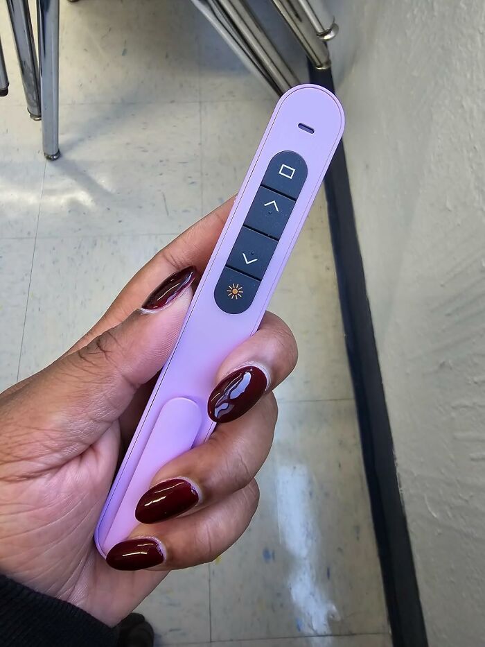 Hand holding a lavender-colored presentation remote, a practical gift for a teacher with patience and caffeine a*******n.