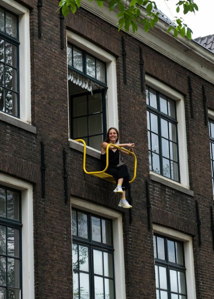 Woman sitting on a yellow chair suspended outside a building window in one of the trippy pictures from another reality.