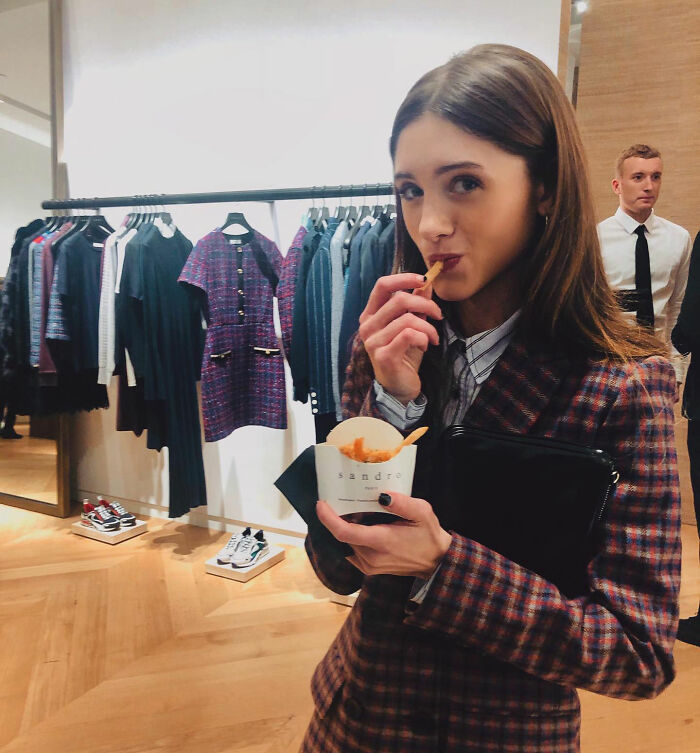 Stranger Things star Natalia Dyer eating fries at a fashion event, fans discussing her appearance and style.