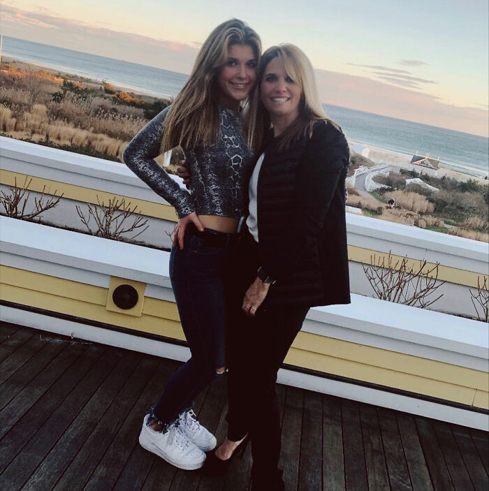 Sorority girl and woman posing on deck with ocean view at luxurious family mansion in sunset light.
