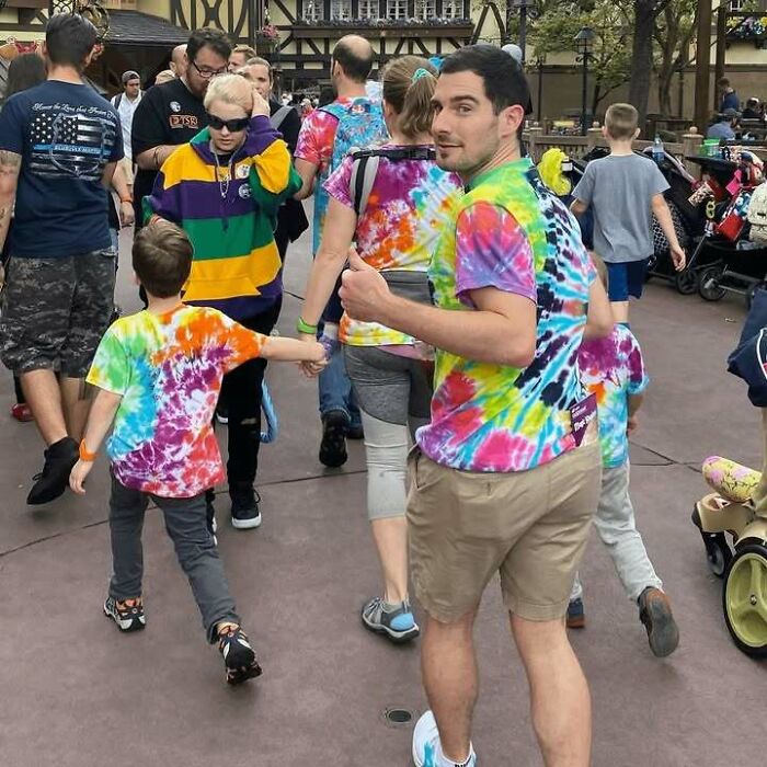Man and children wearing colorful tie-dye shirts in a crowded outdoor area, part of random pics that make you laugh.