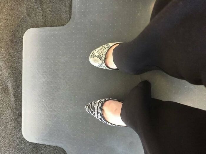 Mismatched shoes with different patterns worn by a person standing on a textured mat in a casual setting.