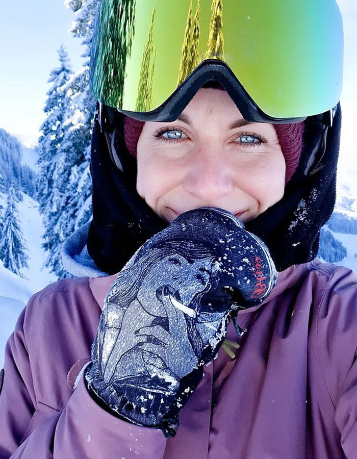 Young woman smiling in ski gear on a snowy mountain, related to woman abandoned to fatally freeze on Austria&rsquo;s peak.