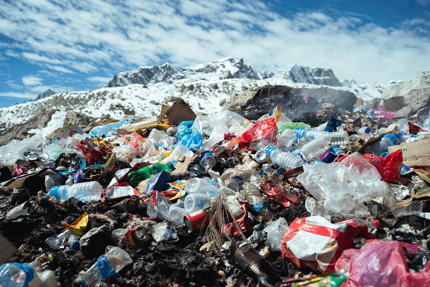 Pile of plastic waste and trash on the ground with mountains in the background showing pollution in the dirtiest countries.
