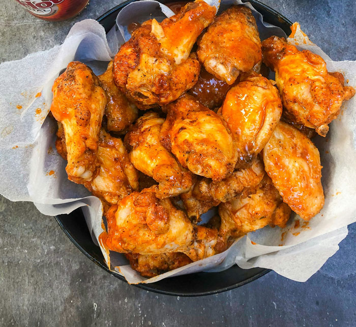 A bowl of crispy buffalo chicken wings coated in spicy sauce, ready for serving as a snack or meal.