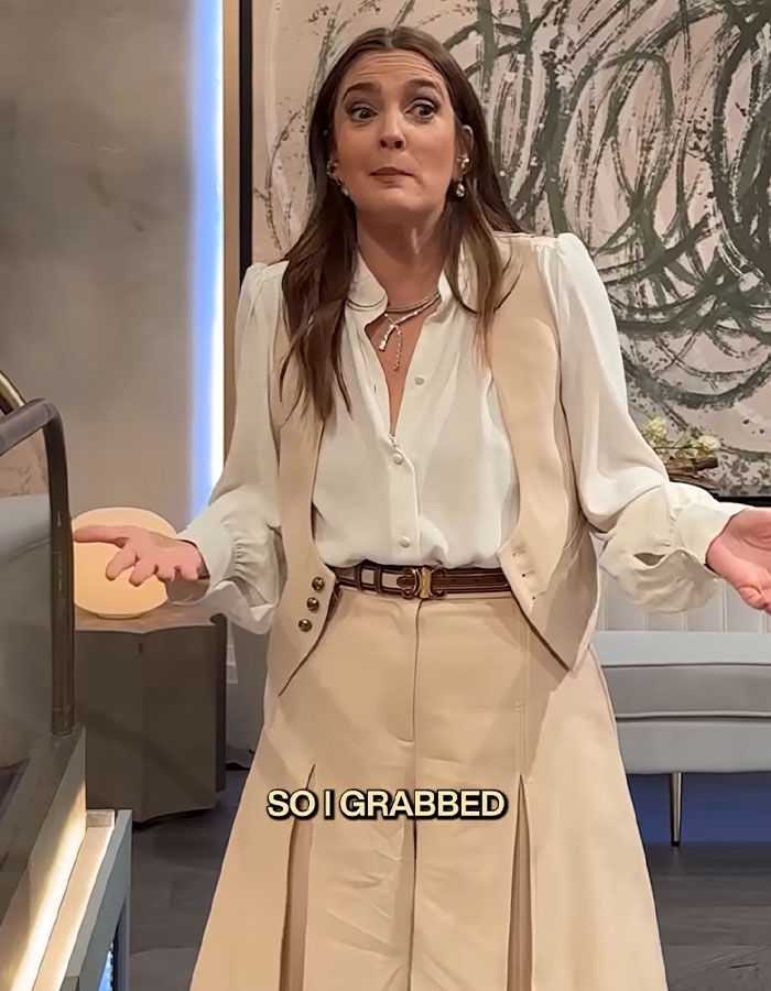 Woman in beige vest and pants reacting with surprise as fan recreates Drew Barrymore&rsquo;s iconic 1989 Oscars dress on her show.