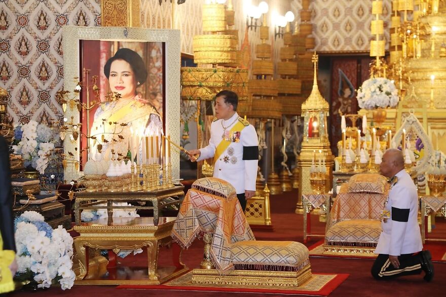 Thai monarch lighting candles in a ceremonial room adorned with golden decorations, reflecting oldest surviving monarchies tradition