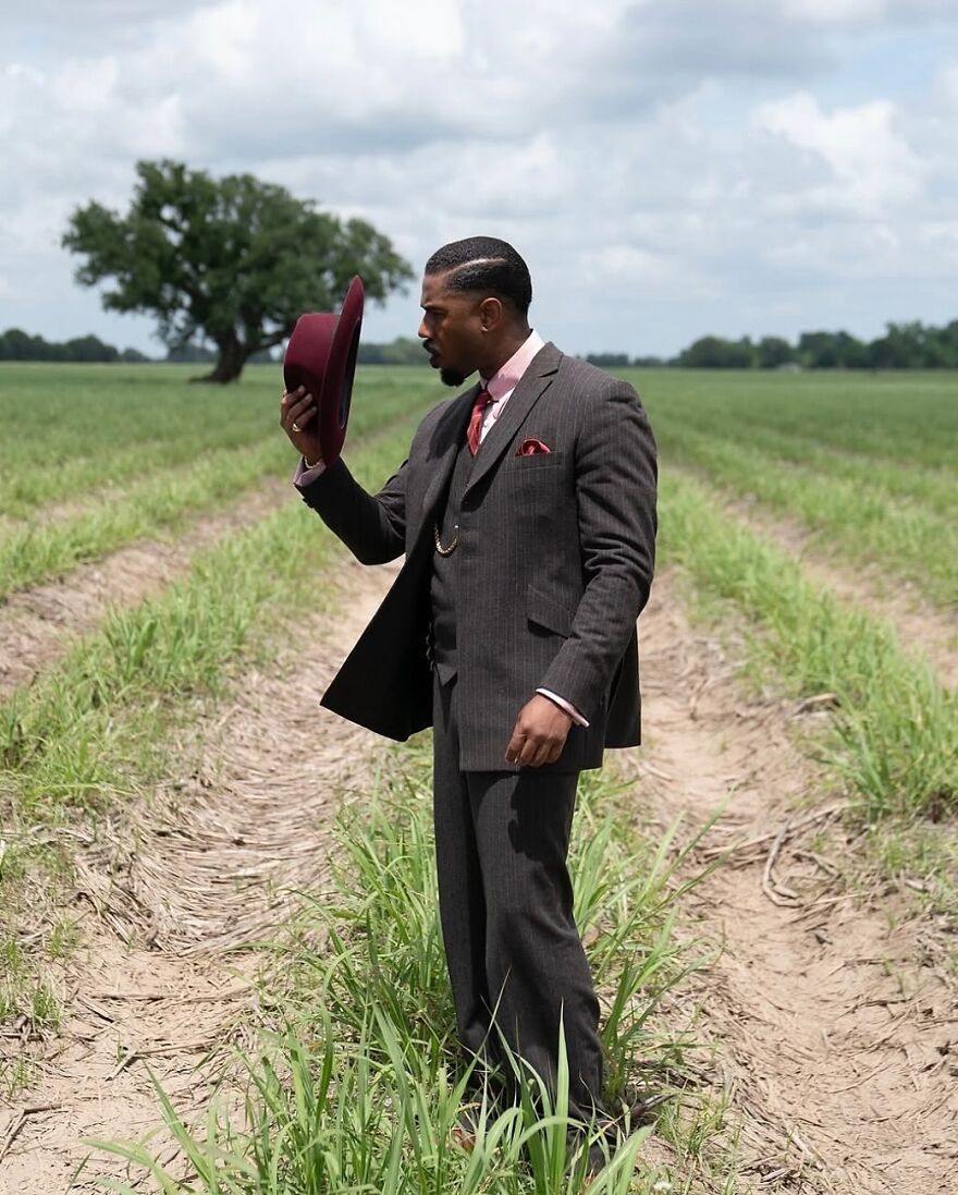Man in a sharp suit holding a burgundy hat standing in a field, representing unforgettable 2025 pop culture moments.