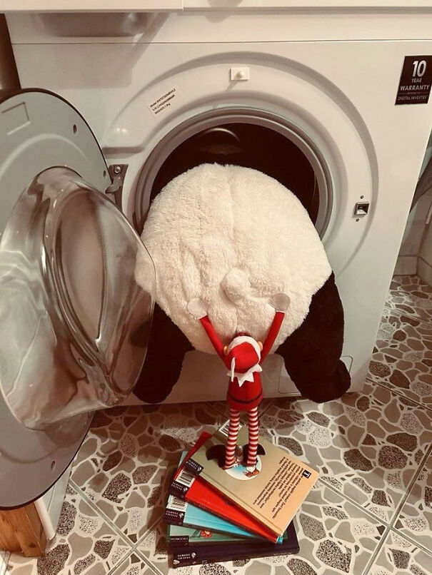 Elf on the shelf mischief scene with elf pushing a stuffed panda into a front-loading washing machine.